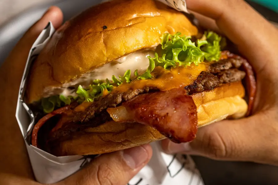 Mano sosteniendo una burger con tocineta