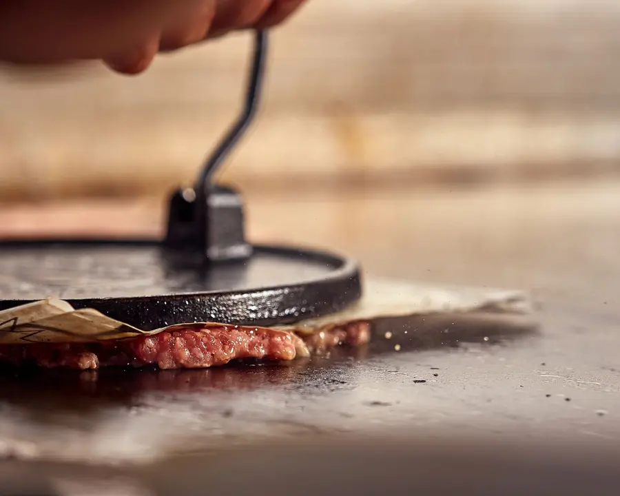 Prensa aplastando la carne en la plancha