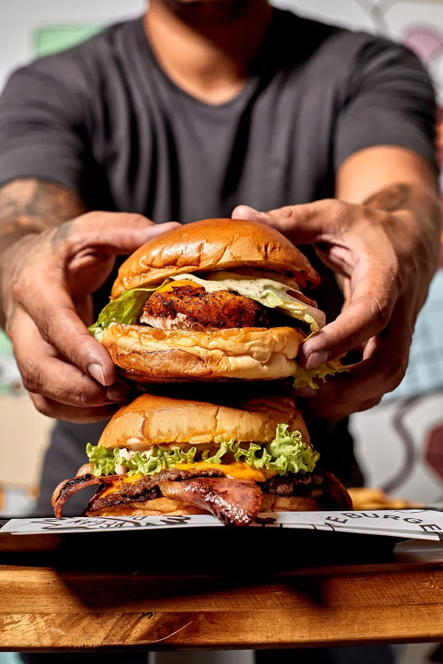 Dos smash burgers apiladas en las manos del cocinero